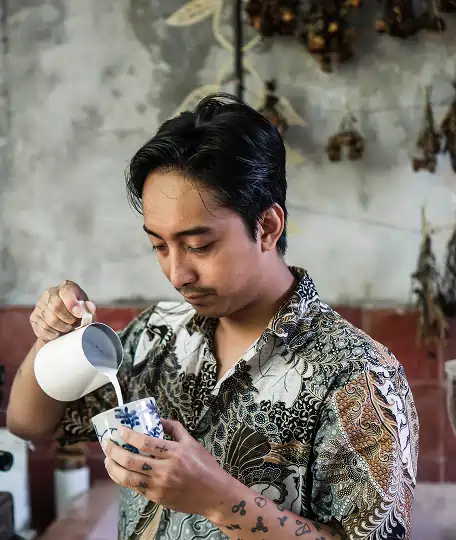 Barista at Yema Bali pouring steamed milk into a handcrafted coffee cup, showcasing the artisanal coffesshop experience in the Canggu cafe scene.