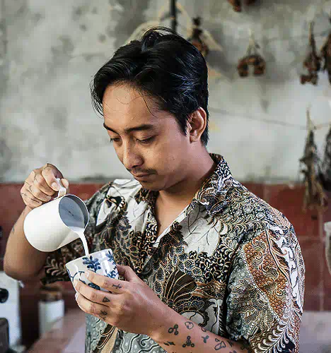 Barista pouring steamed milk into a fresh coffee at Yema Canggu coffeeshop, captured in a quiet moment of morning preparation and artisanal focus.