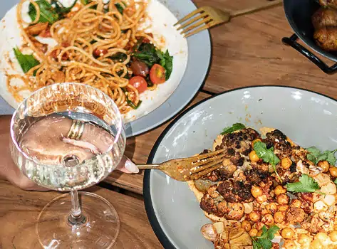 Roasted cauliflower with chickpeas, pasta, and potatoes served with white wine at Yema Kitchen, a Canggu restaurant offering fresh Mediterranean food.
